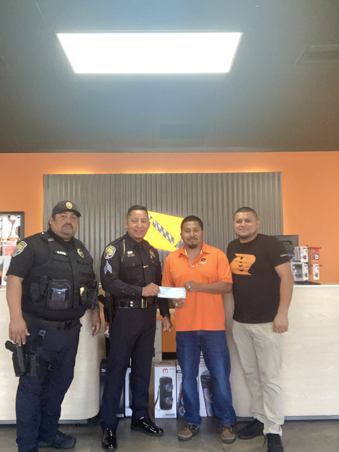 Owners of the Boost stores, Valentin Bautista and Ceferino Espinoza, donated a check to Okeechobee City Police to help cover cost of Honor Guard uniforms. Sgt. Almazan and Lt. Reyna accept the donation from the store owners.